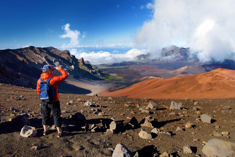 Tourist hiking in Haleakala volcano crater on the Sliding Sands trail. Beautiful view of the crater floor and the cinder cones below