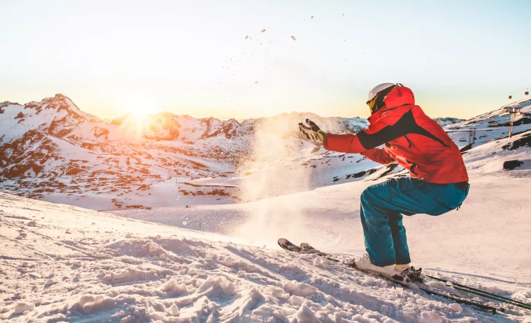 Skier playing with snow at sunset on ski mountain resort