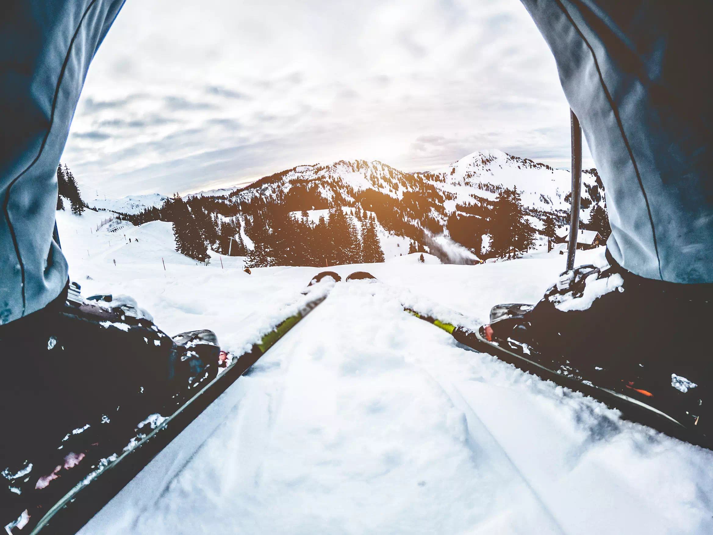 Skier athlete standing in front of sunset in ski resort ready for downhill - Winter extreme sport concept with person on top of the mountain ready to ride down - Focus on mountains