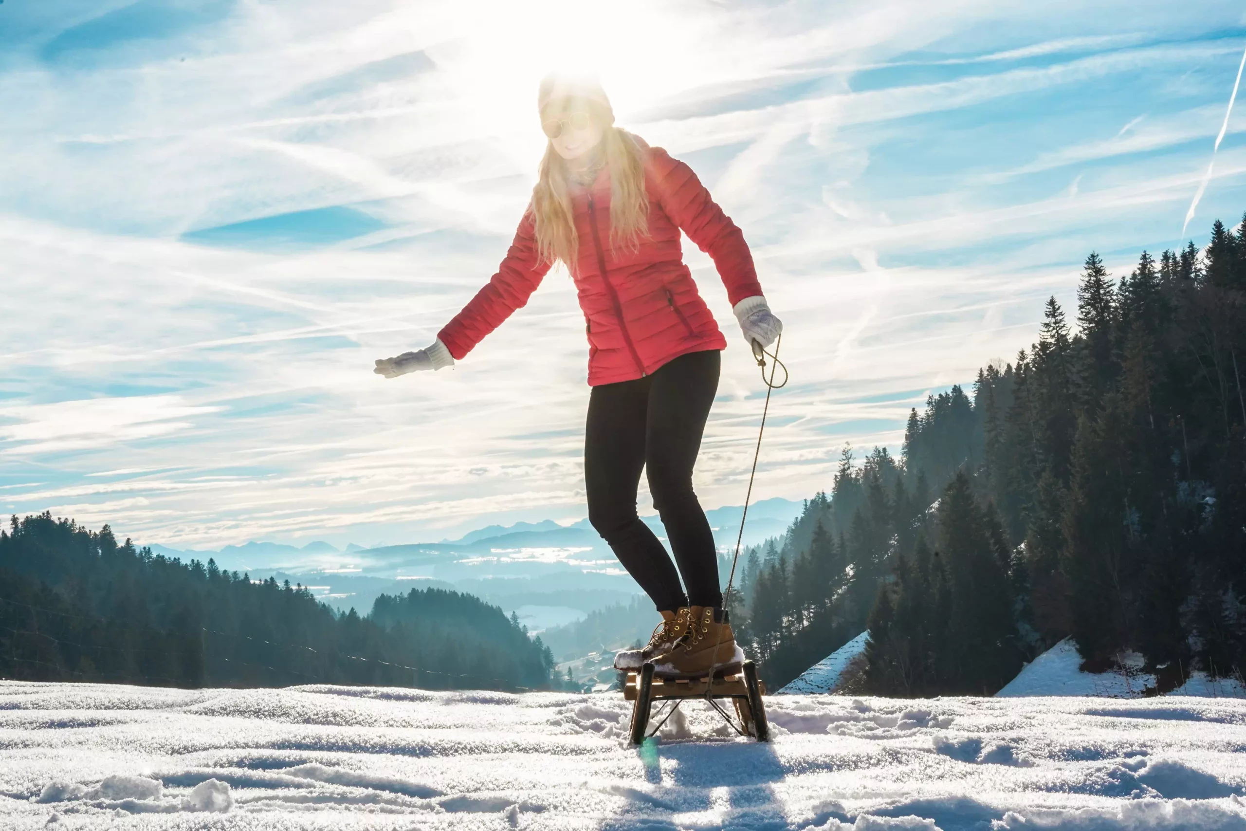 Young woman speeding with vintage sledding on snow high mountain - Happy girl having fun in white week vacation- Travel, winter sport, holiday concept - Main focus on her feet