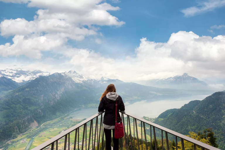 Woman traverler looking aerial view of the city district and Interlaken from viewpoint at Harder Kulm in Interlaken, Bern, Switzerland