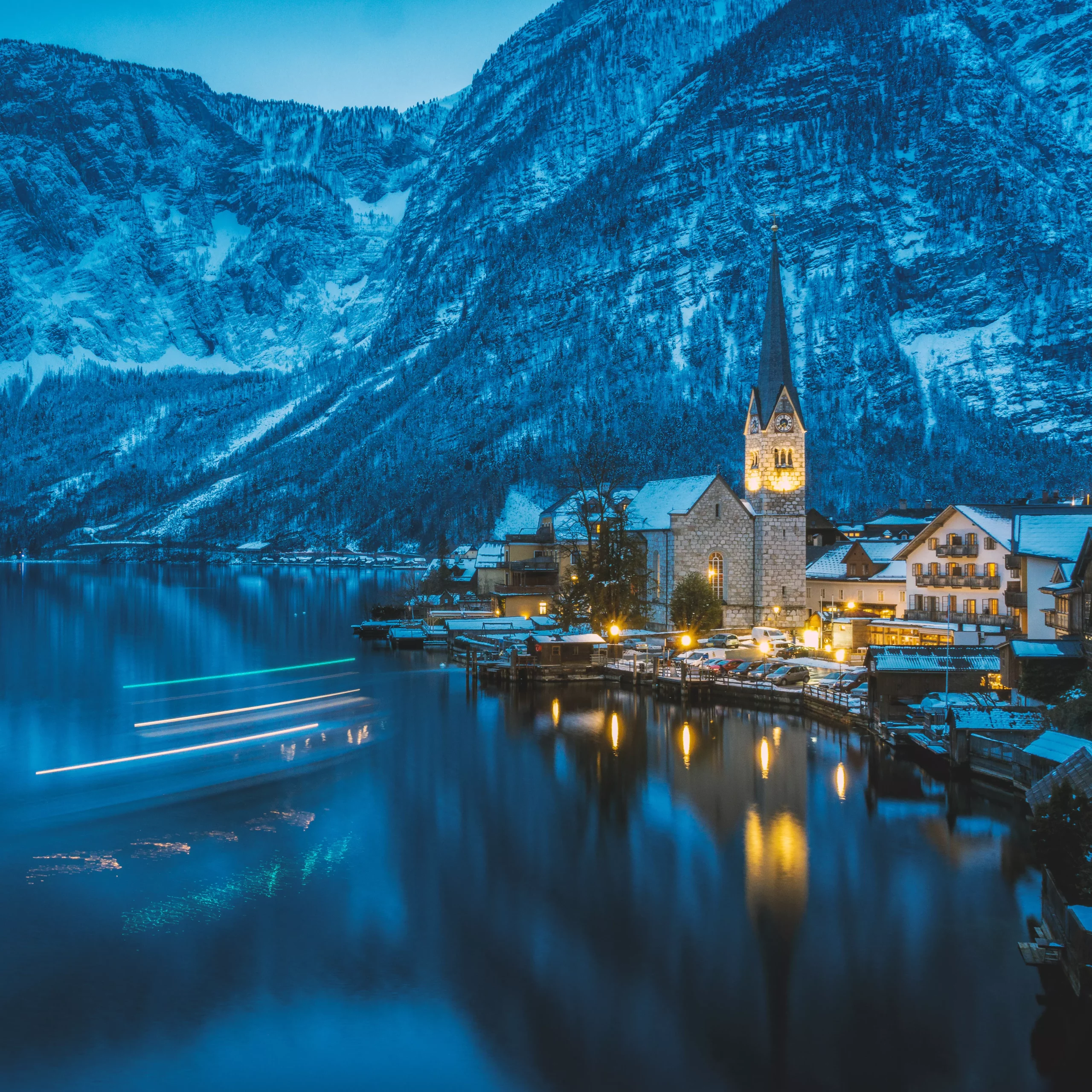 Hallstatt at night with lightstripes of an arriving little ferryboat, austria