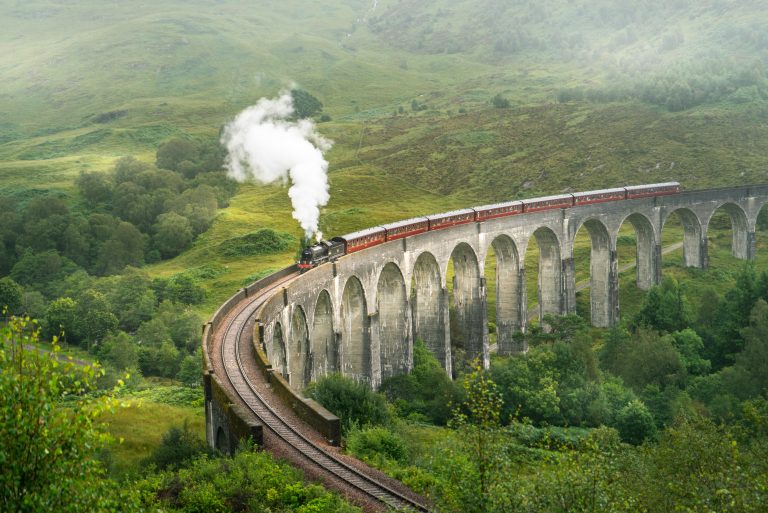 Train going over the Glenfinnan railway viaduct in Scotland, UK