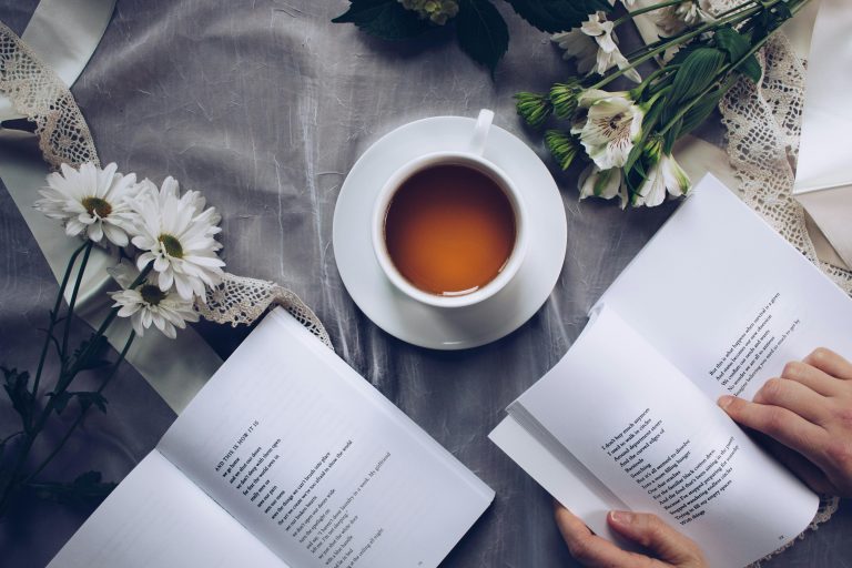 Inviting cozy reading setup with tea, poetry books, and fresh flowers on a table